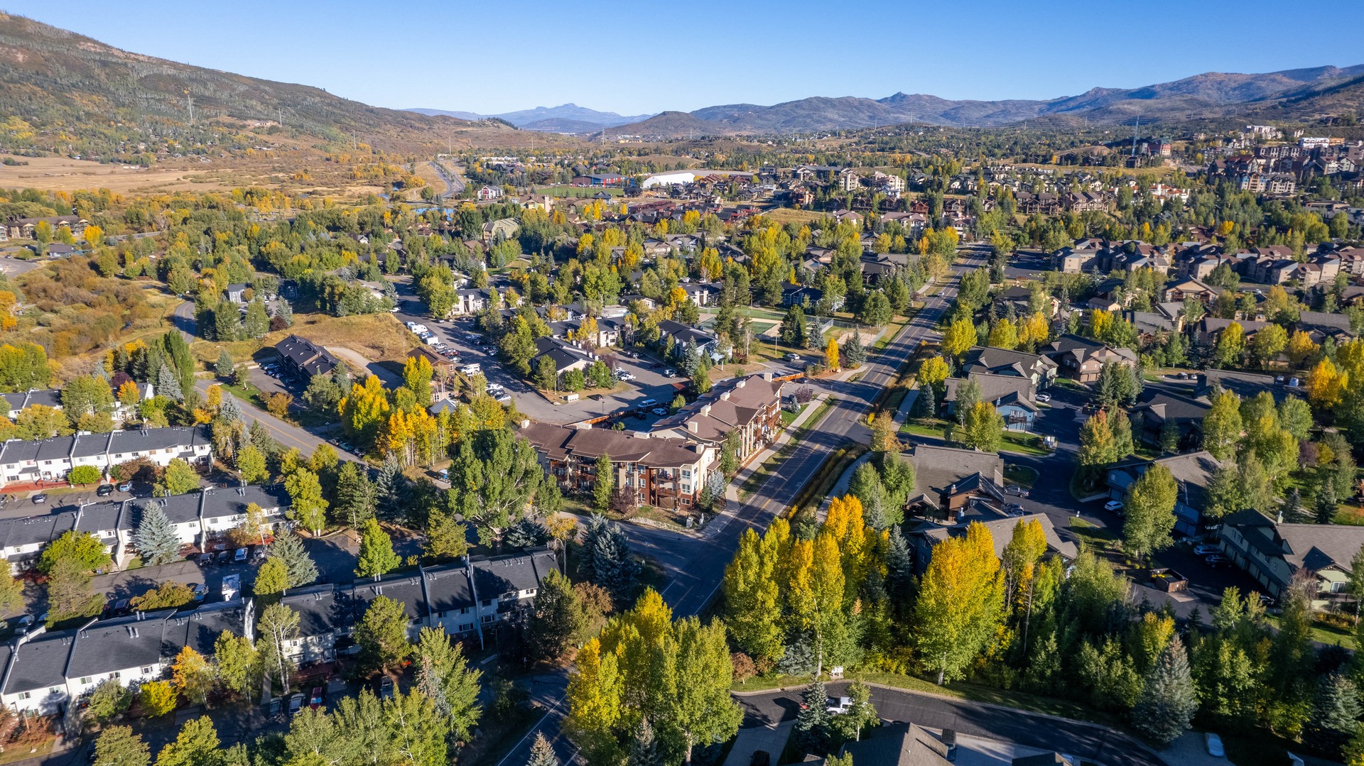 A small town with houses and trees in the foreground and mountains in the background.